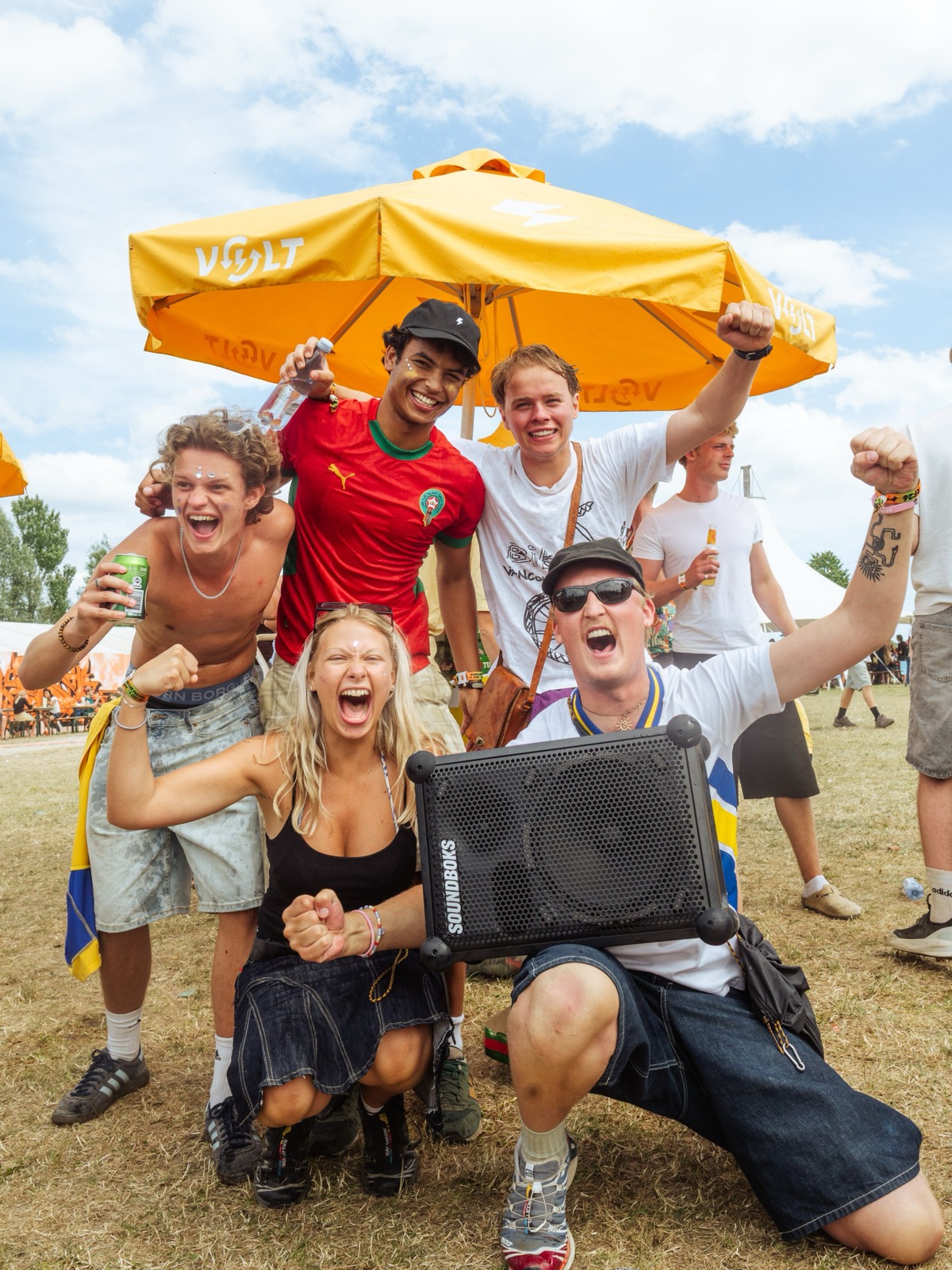 Happy festival guests with a Soundboks under a Volt parasol