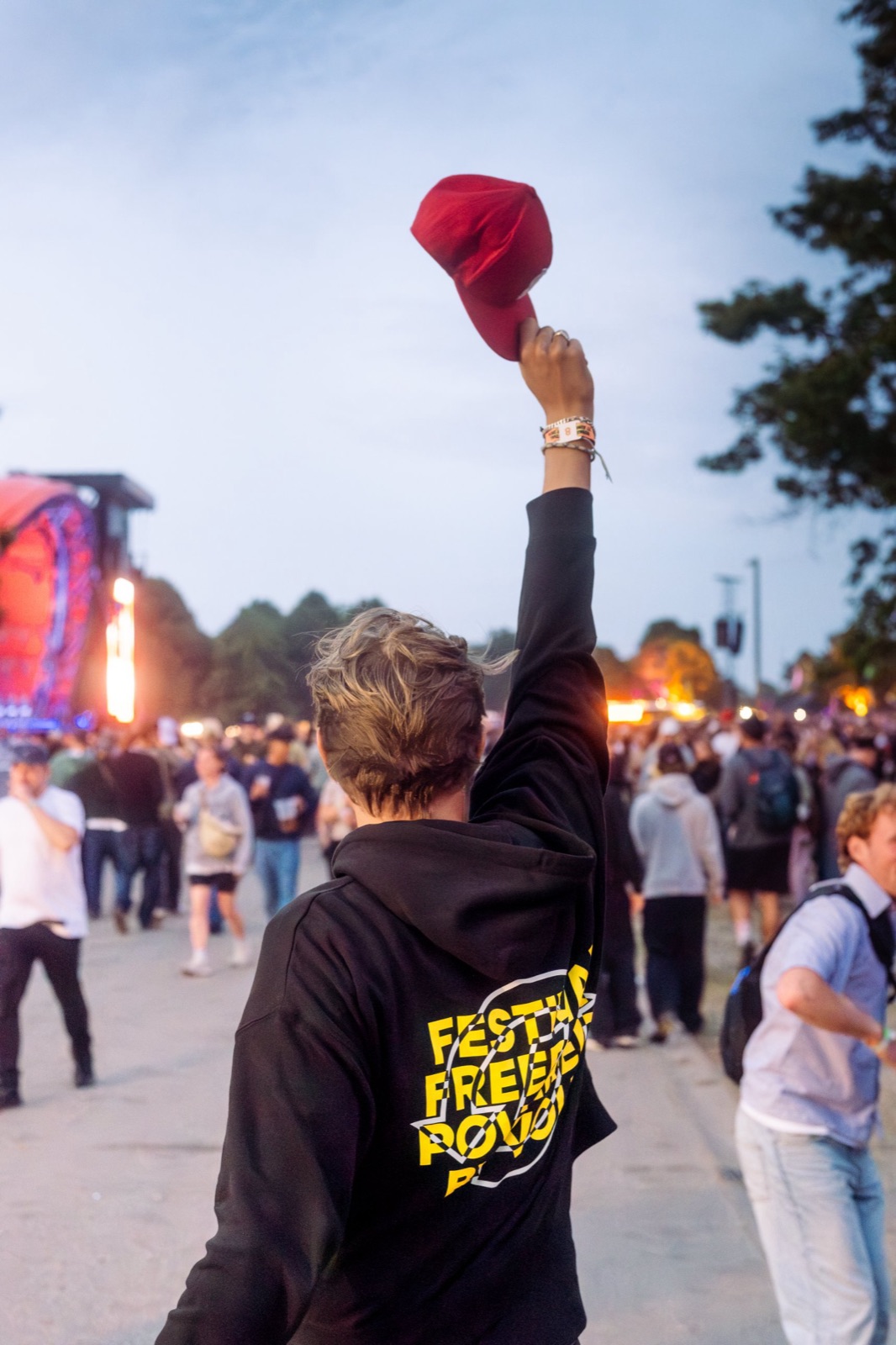 Festival guest in a Volt hoodie raising his cap in front of the stage